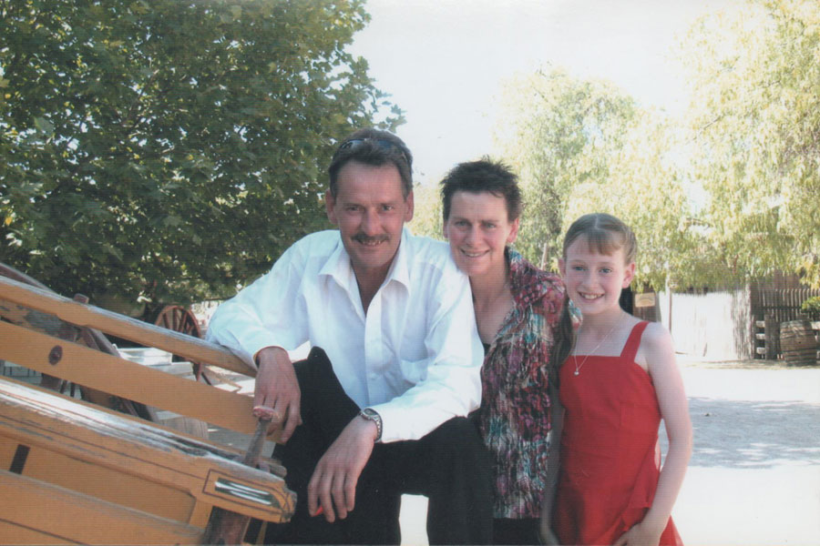 Brian crouching down next to his wife and daughter. 