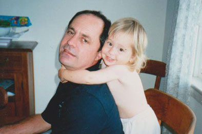 Jess as a child holding onto her father who is wearing a navy blue shirt. 