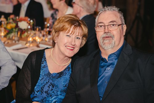 Susan sitting next to her husband at dinner smiling.