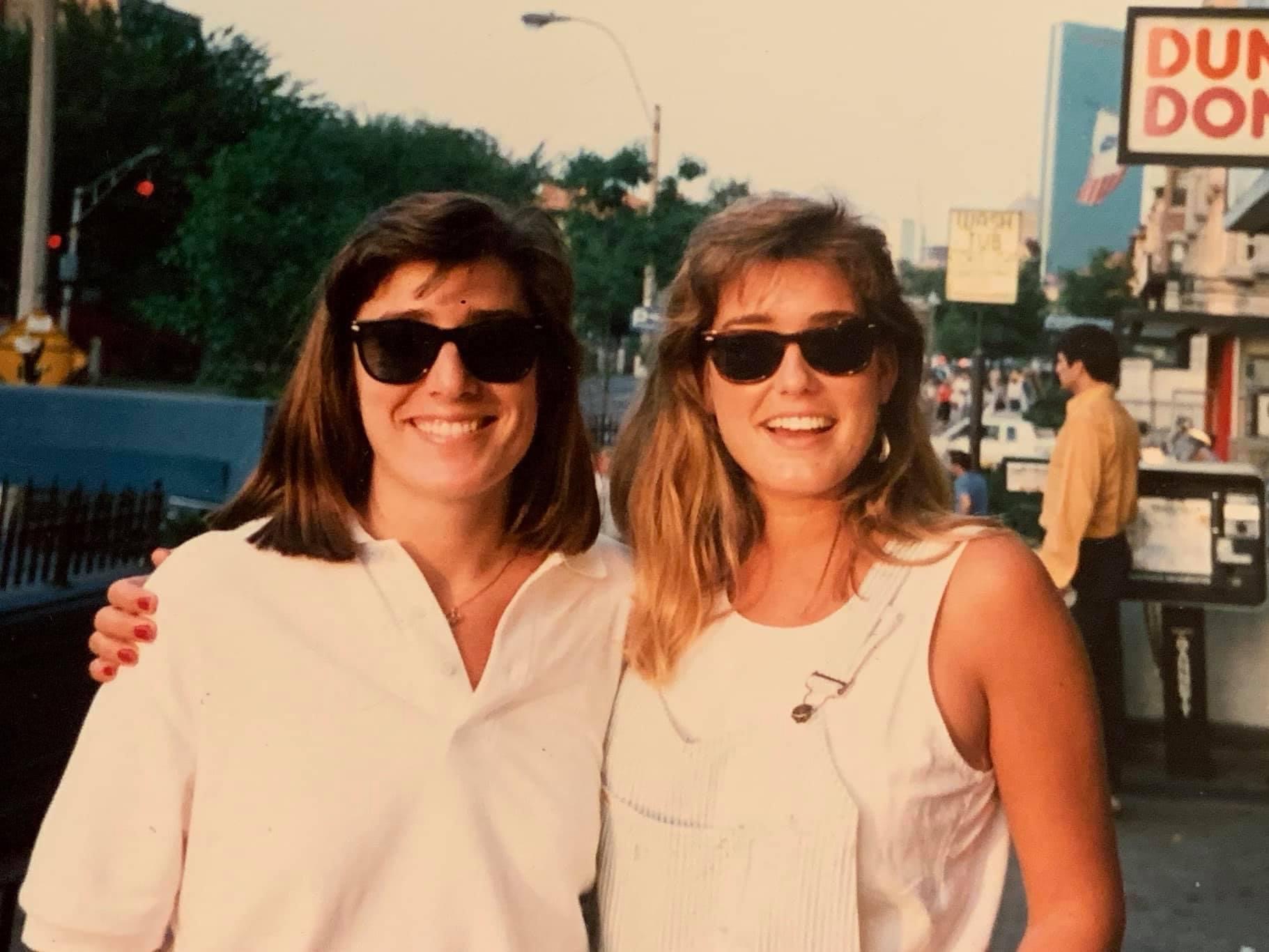 Kathy and Kelly, standing on the street, smiling at the camera. 
